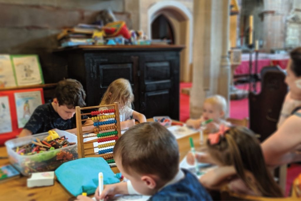 Children drawing and colouring at a table in church