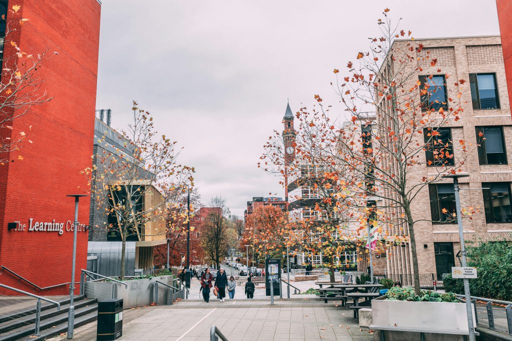A university campus in autumn, with a clock tower in the distance